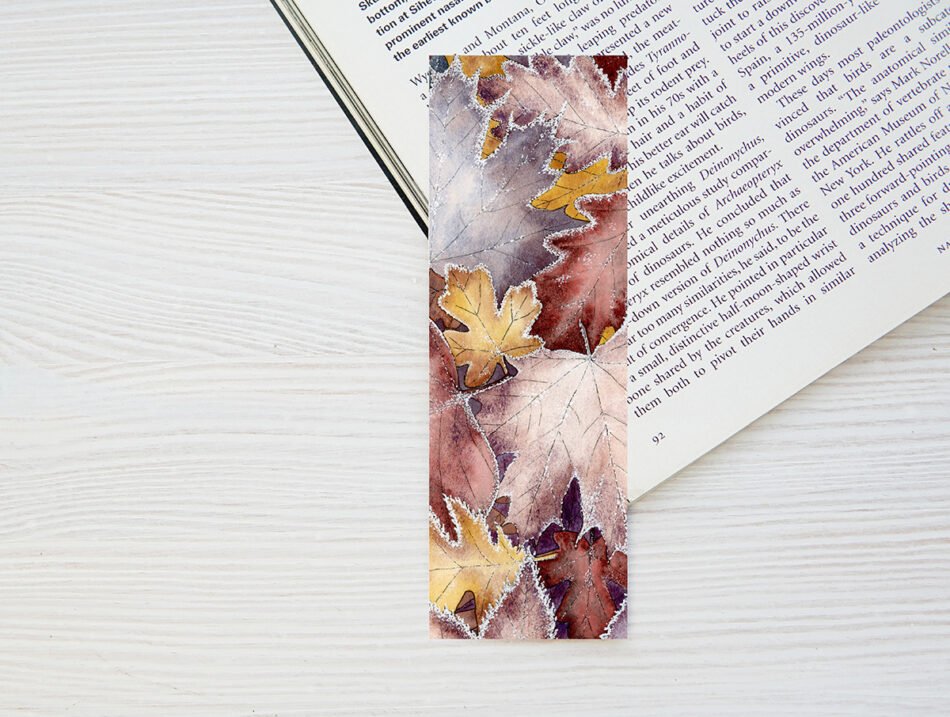 Marque-page petit format glissé dans un livre de poche illustration botanique à l'aquarelle d'un feuillage d'automne et givre