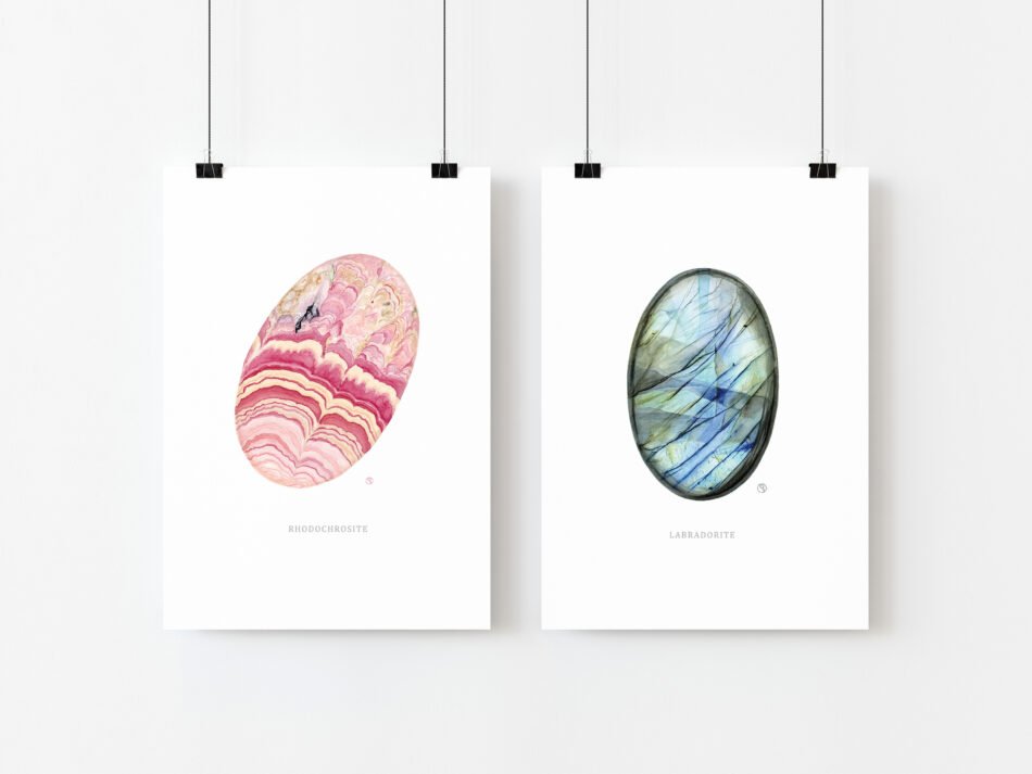 Duo de cartes postales représentant des minéraux de collection labradorite et rhodochrosite suspendues par des pinces métalliques noires sur fond blanc
