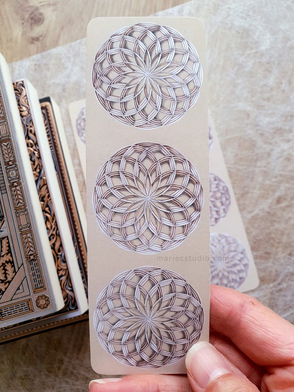 Gros plan sur un marque-page réalisé à partir d'un dessin original de géométrie sacrée avec des rosaces géométriques avec un jeu d'ombres et de lumière